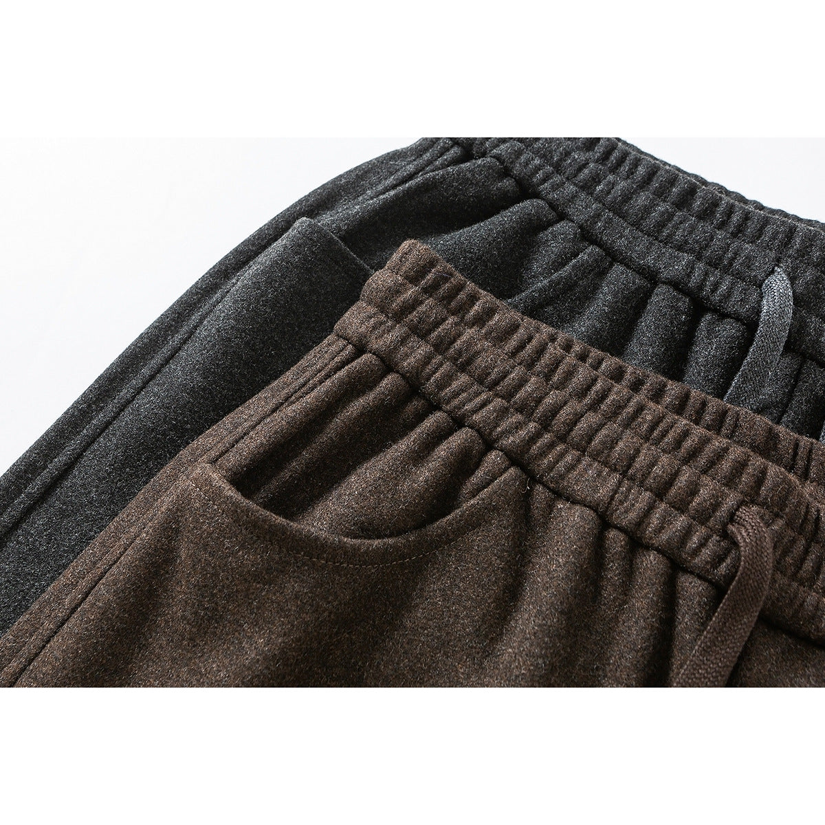 Close-up of charcoal and brown pants showing elastic drawstring waistbands and front pockets.