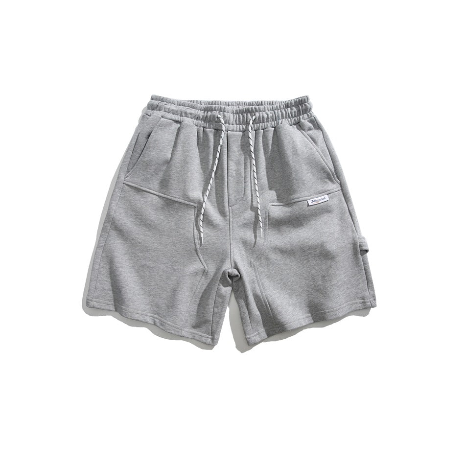 Front view of gray knee-length shorts with an elastic drawstring waist, angled front pockets, and a small label.