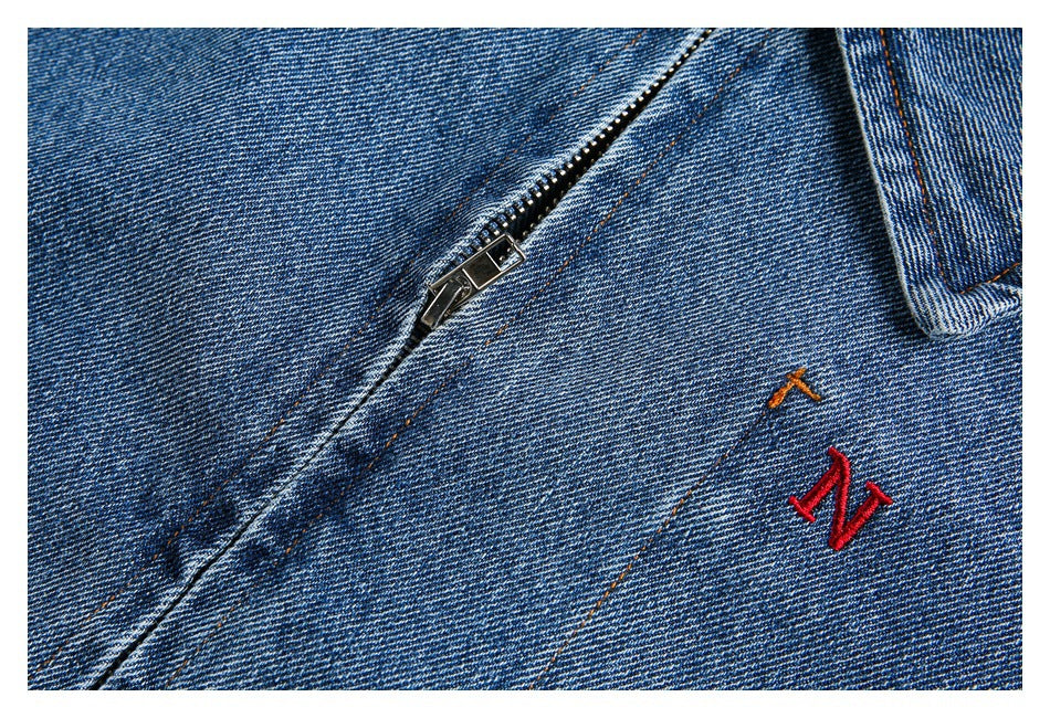 Close-up showing the jacket's metal zipper, denim stitching and small embroidered accents.