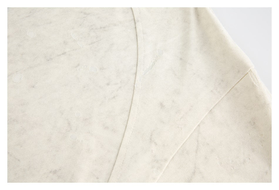 Close-up of ivory mottled fabric showing a seam and scattered distressed marks.