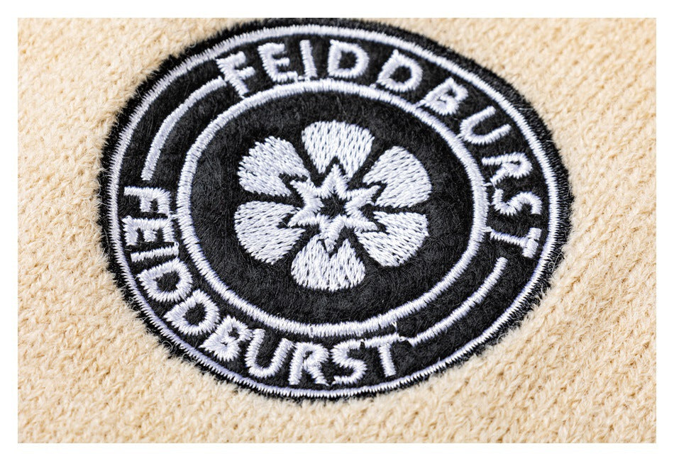 Close-up of a black-and-white circular embroidered patch on cream knit fabric.