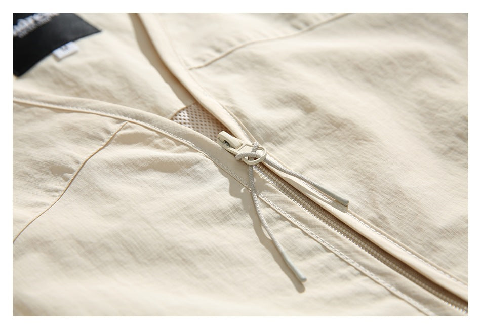 Close-up of the ivory jacket's zipper, corded pull, stitching, and textured fabric surface.