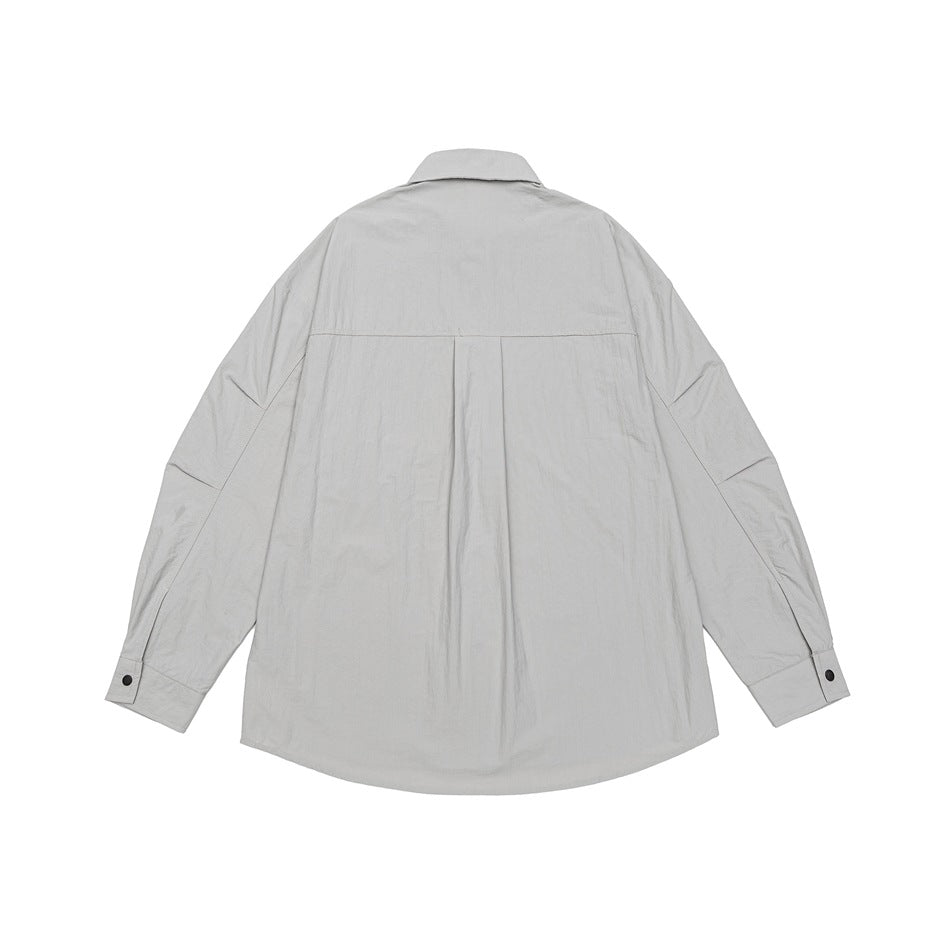 Back view of a light gray long-sleeve collared shirt with a center pleat and buttoned cuffs.