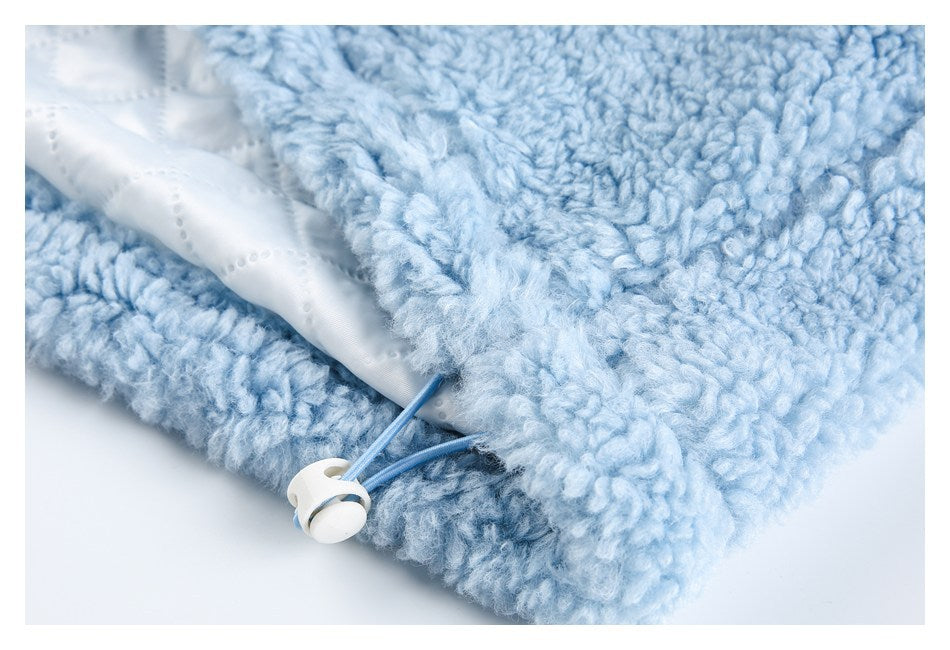 Close-up of pale blue plush garment lining and a small white toggle attached to a blue cord.