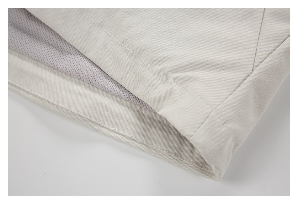 Close-up of a pale beige garment hem with exposed gray mesh lining and stitched seams.