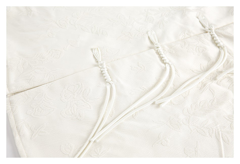 Close-up of several ivory braided frog closures across floral-patterned fabric.