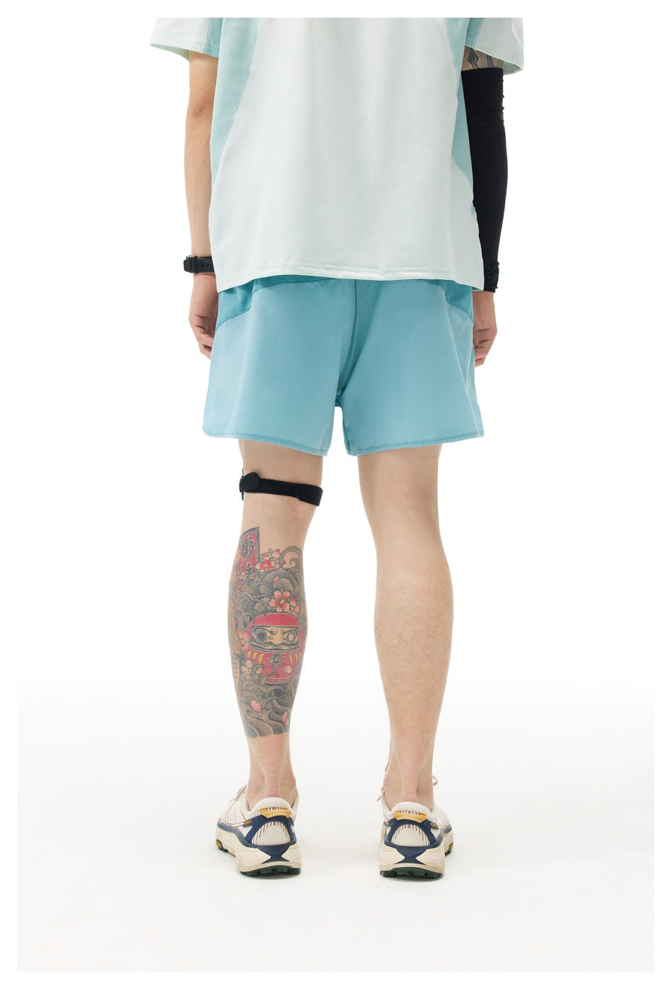 Rear view of a model wearing light blue athletic shorts and a white shirt.