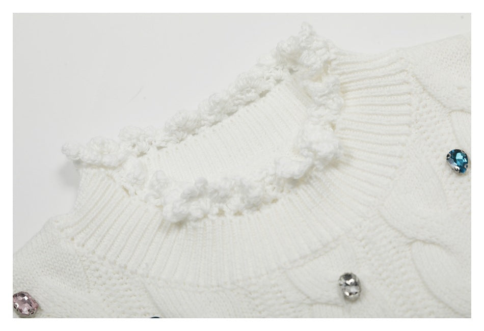 Close-up of a white sweater's ruffled ribbed neckline and colorful jeweled embellishments.