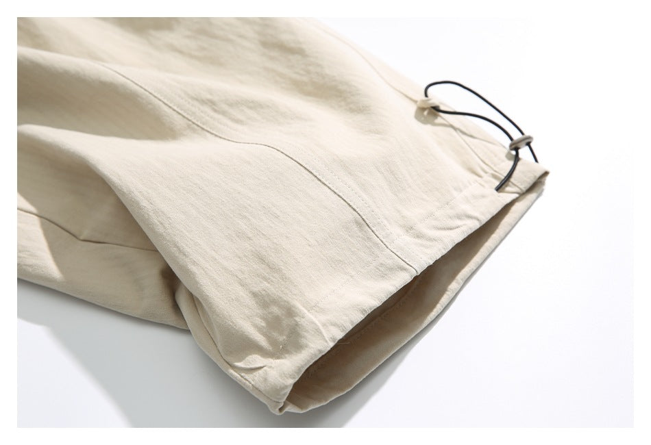 Close-up of a beige pants hem with a black adjustable cord and toggle.