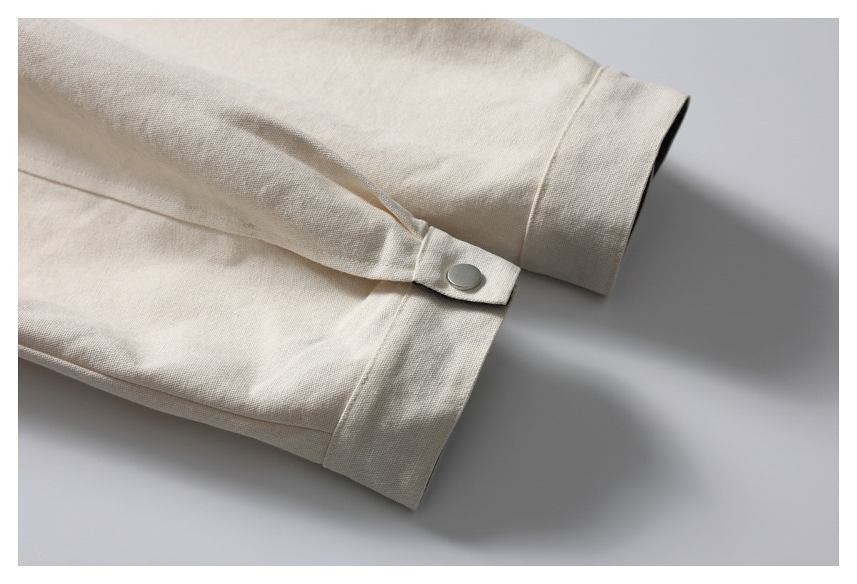 Close-up of an ivory jacket sleeve cuff with a snap-fastened adjustment tab.