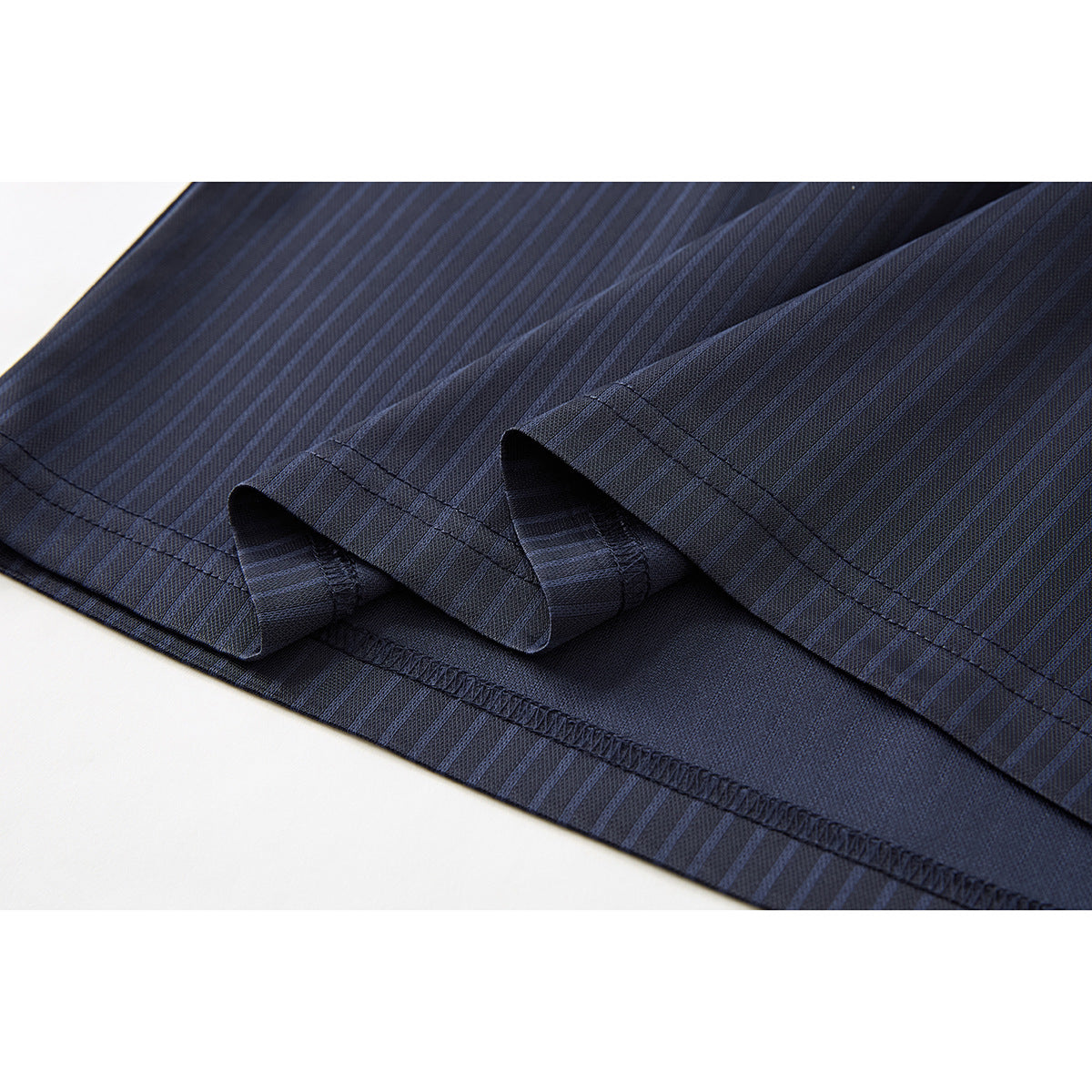 Close-up of the navy pinstriped polo shirt’s folded hem and stitched seams.
