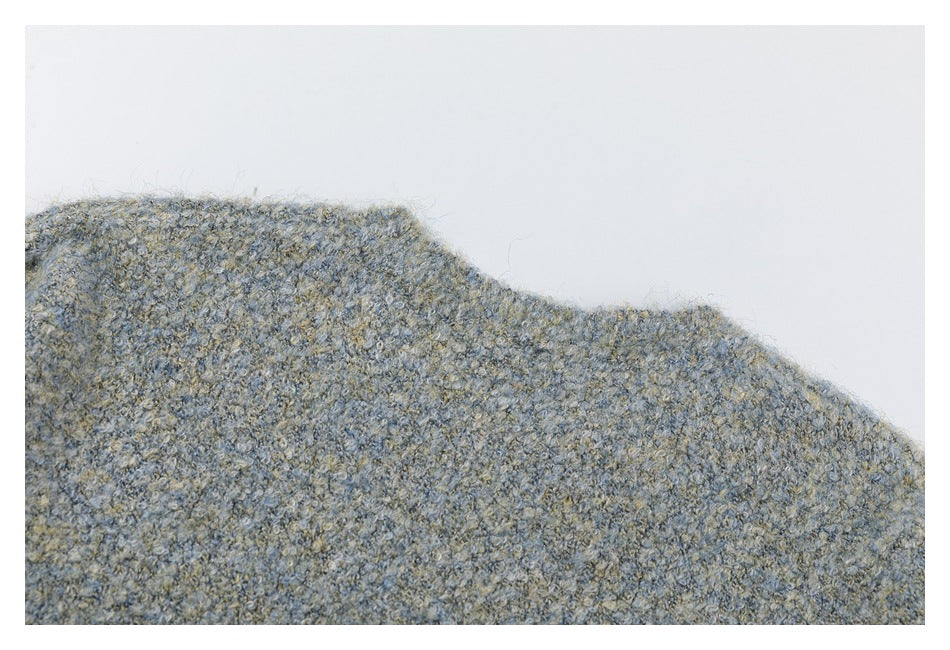 Close view of a shoulder edge on a mottled gray-blue and beige knit garment against white.