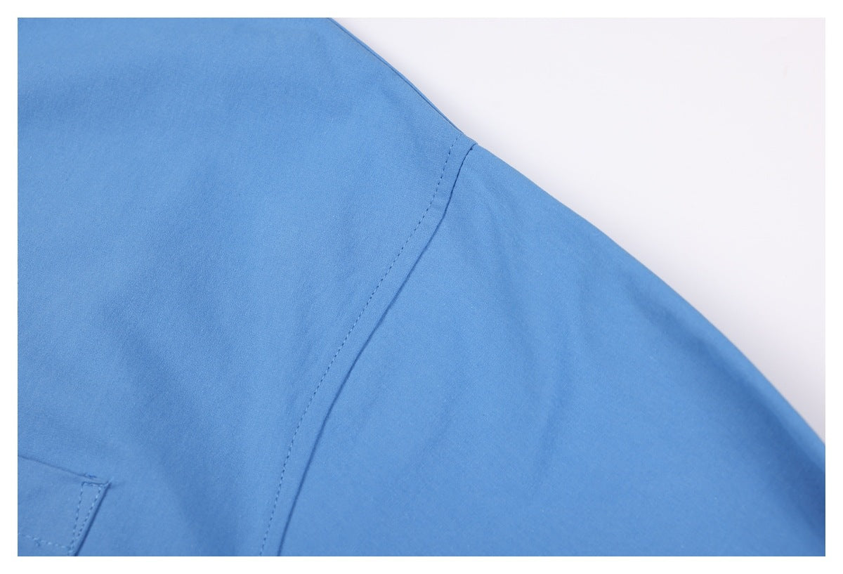 Close-up of a blue shirt’s shoulder seam and sleeve against a white background.