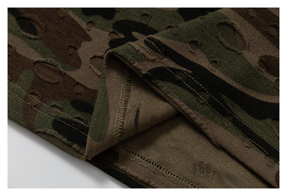 Close-up of a camouflage garment showing its folded hem and interior overlock stitching.