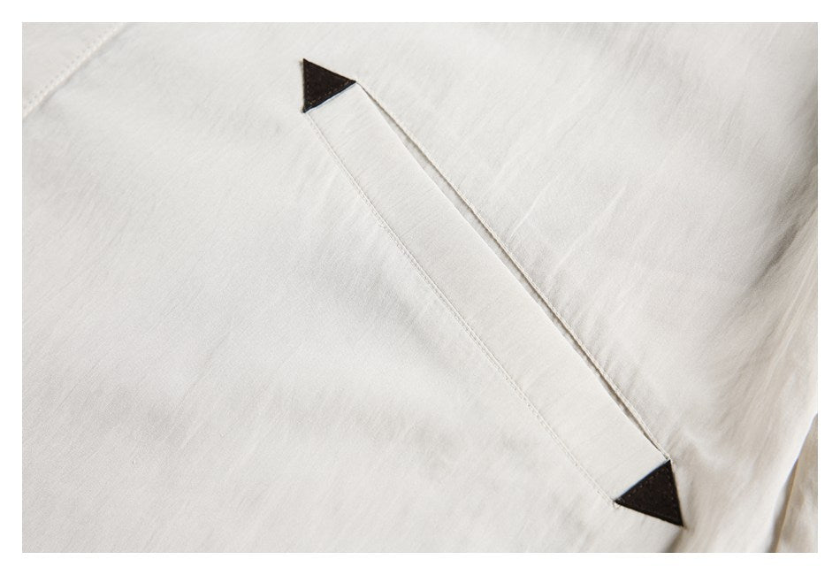 Close-up of a light beige shirt pocket opening with dark triangular end accents.