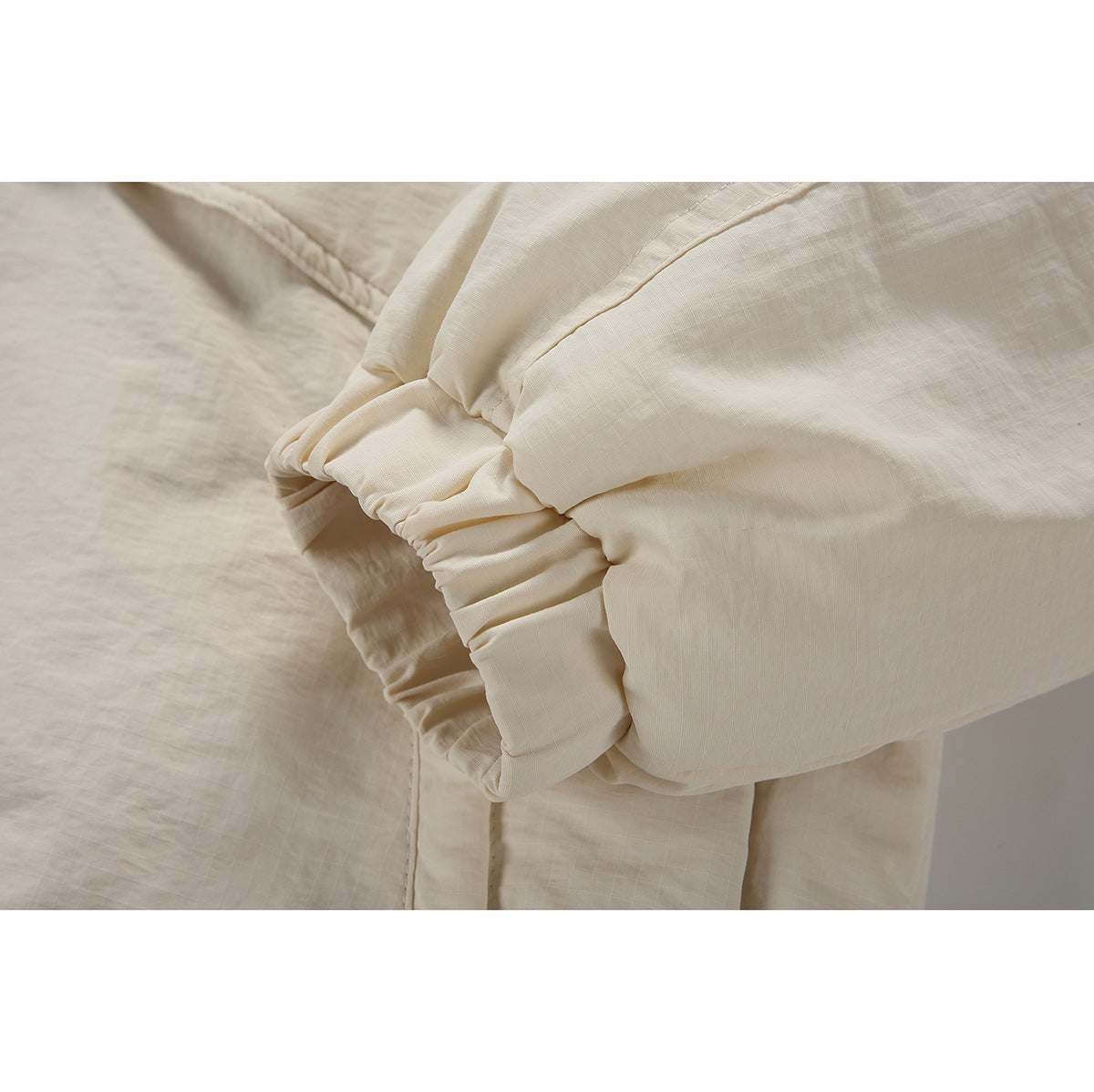 Close-up of the cream jacket sleeve cuff, showing its gathered elastic construction and stitching.