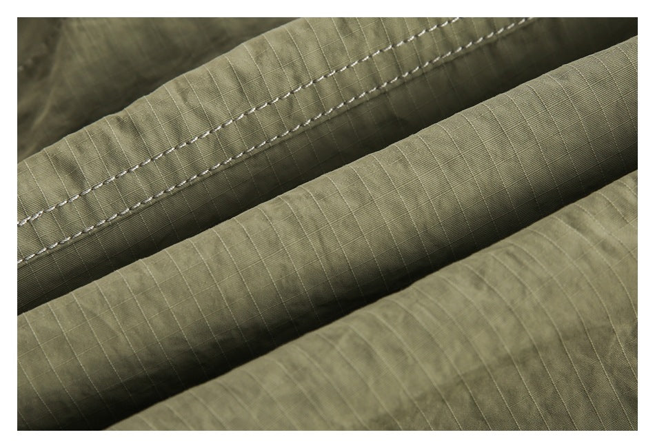 Macro view of olive ripstop fabric folds and reinforced seam stitching.