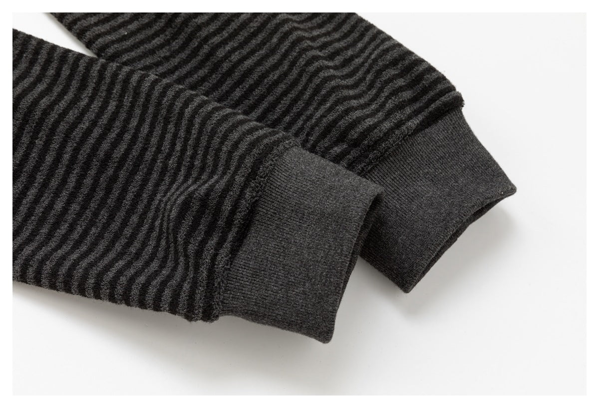 Close-up of a charcoal garment sleeve with a wide ribbed cuff and wavy textured stripes.