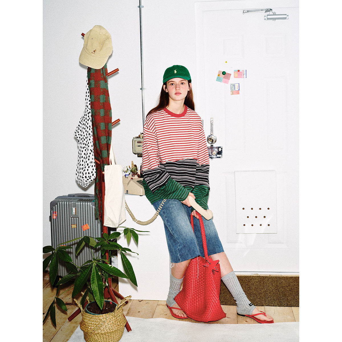 Model wearing an oversized red, black, and green striped color-block shirt with blue denim culottes.