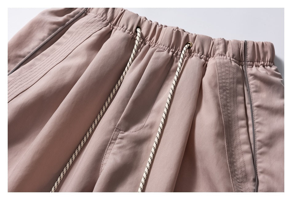 Close-up of the mauve pants' elastic waistband, drawstrings, front pocket and stitched piping.