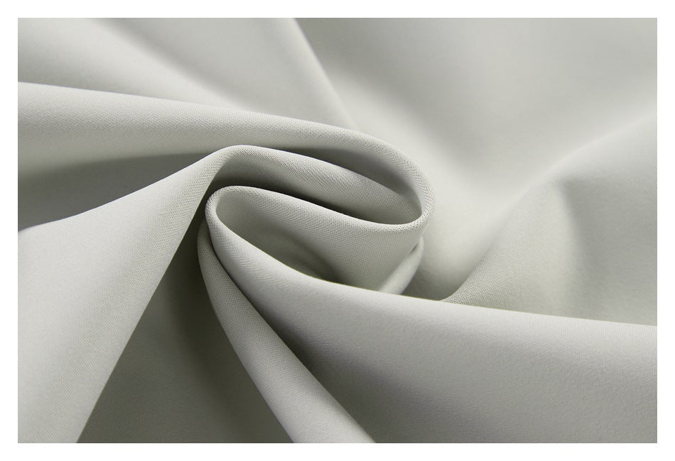 Close-up of smooth light gray fabric curled into soft folds.