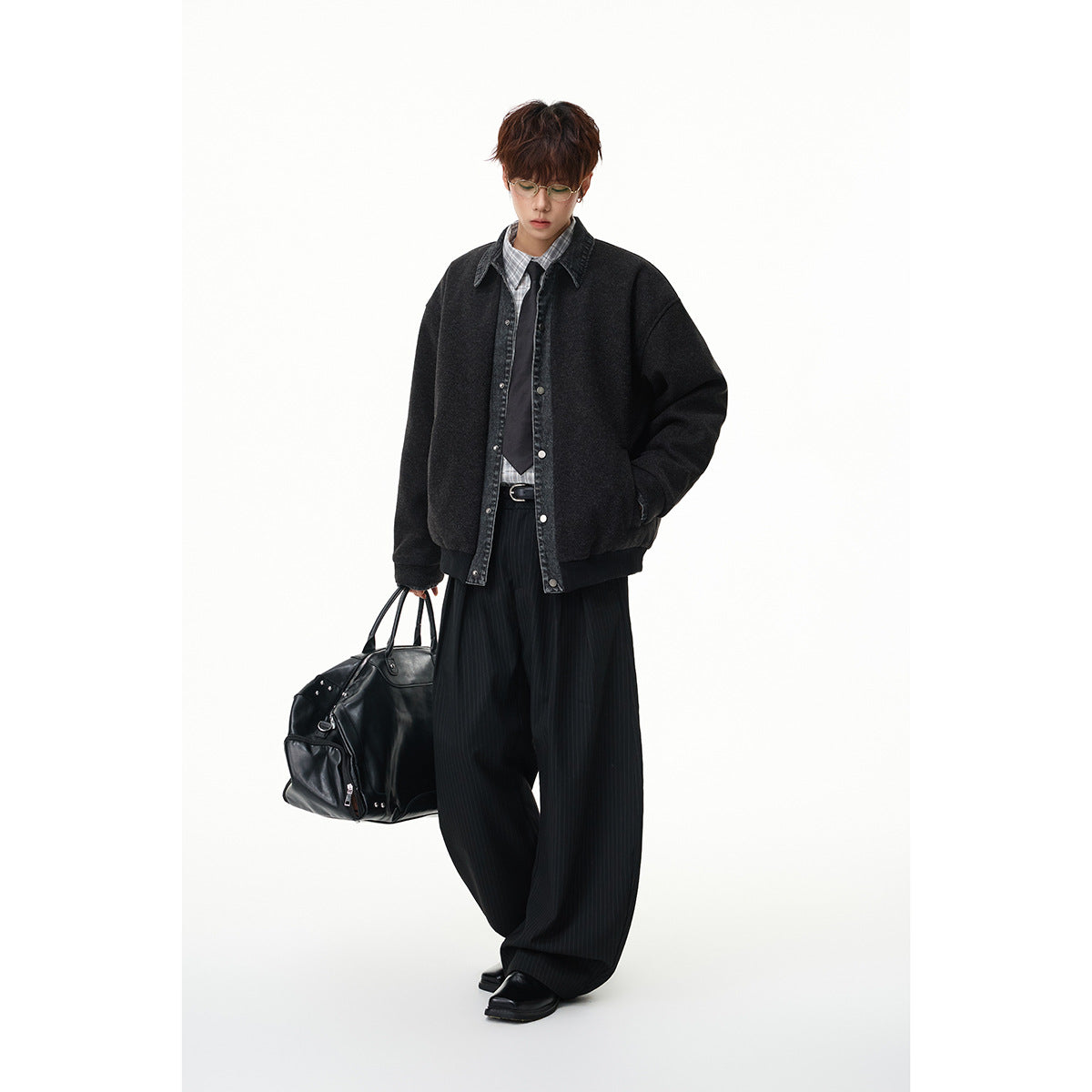 Full-length view of a model wearing the charcoal jacket with dark denim trim, checked shirt, tie, and wide-leg trousers.