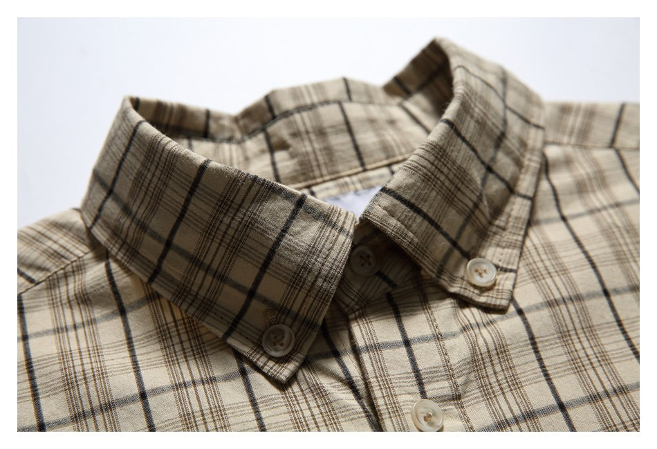 Close-up of a beige plaid shirt collar with dark intersecting lines and light buttons.
