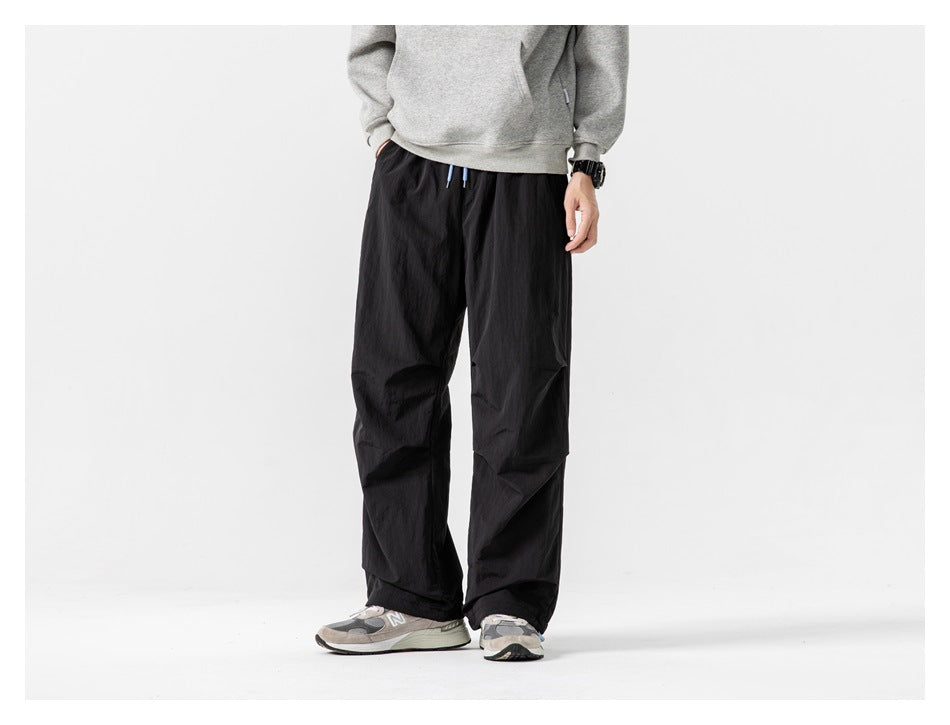 Cropped model wearing loose black pants in a front view with gray sneakers.