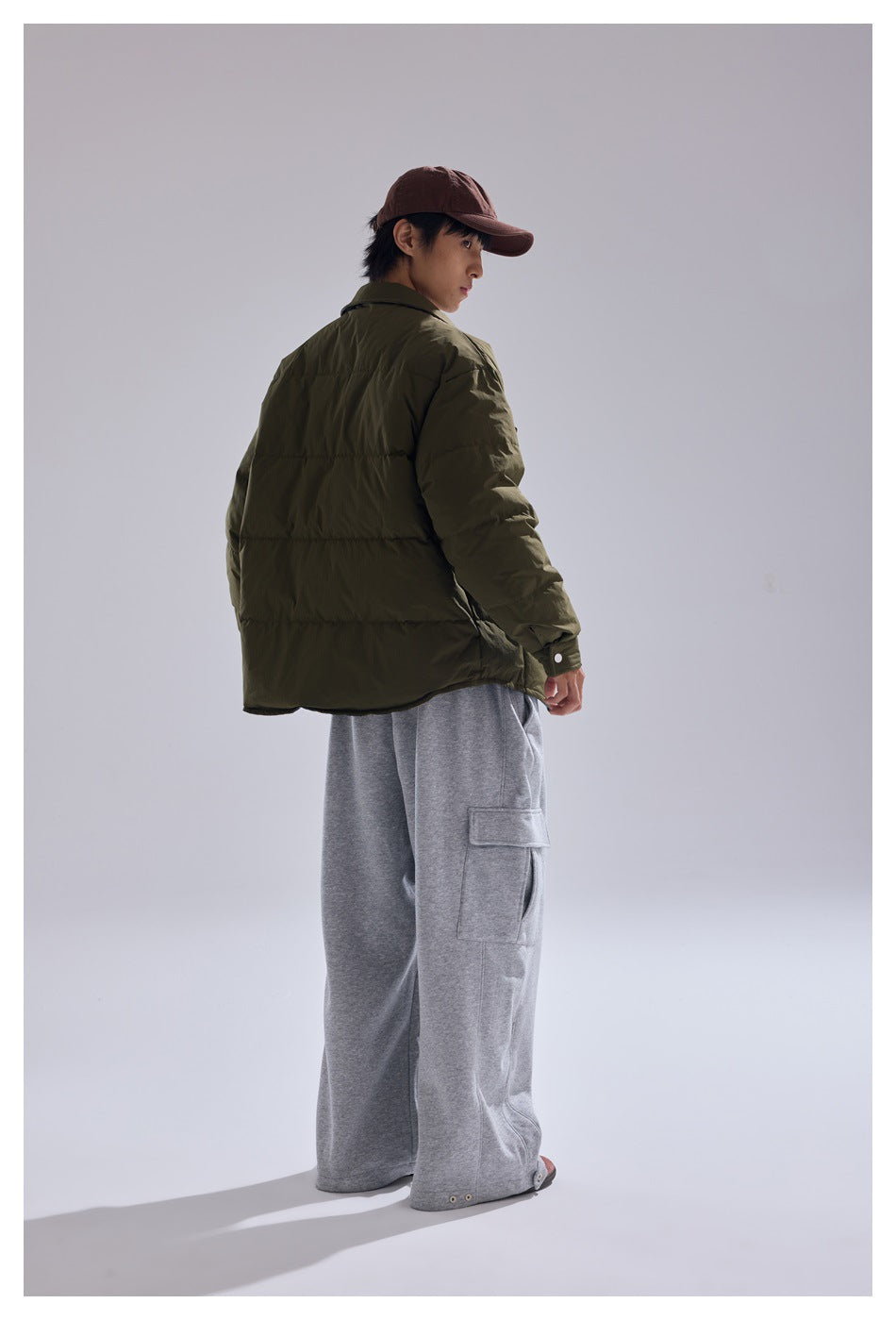 Model wearing the army green quilted jacket and gray cargo sweatpants, seen from the back