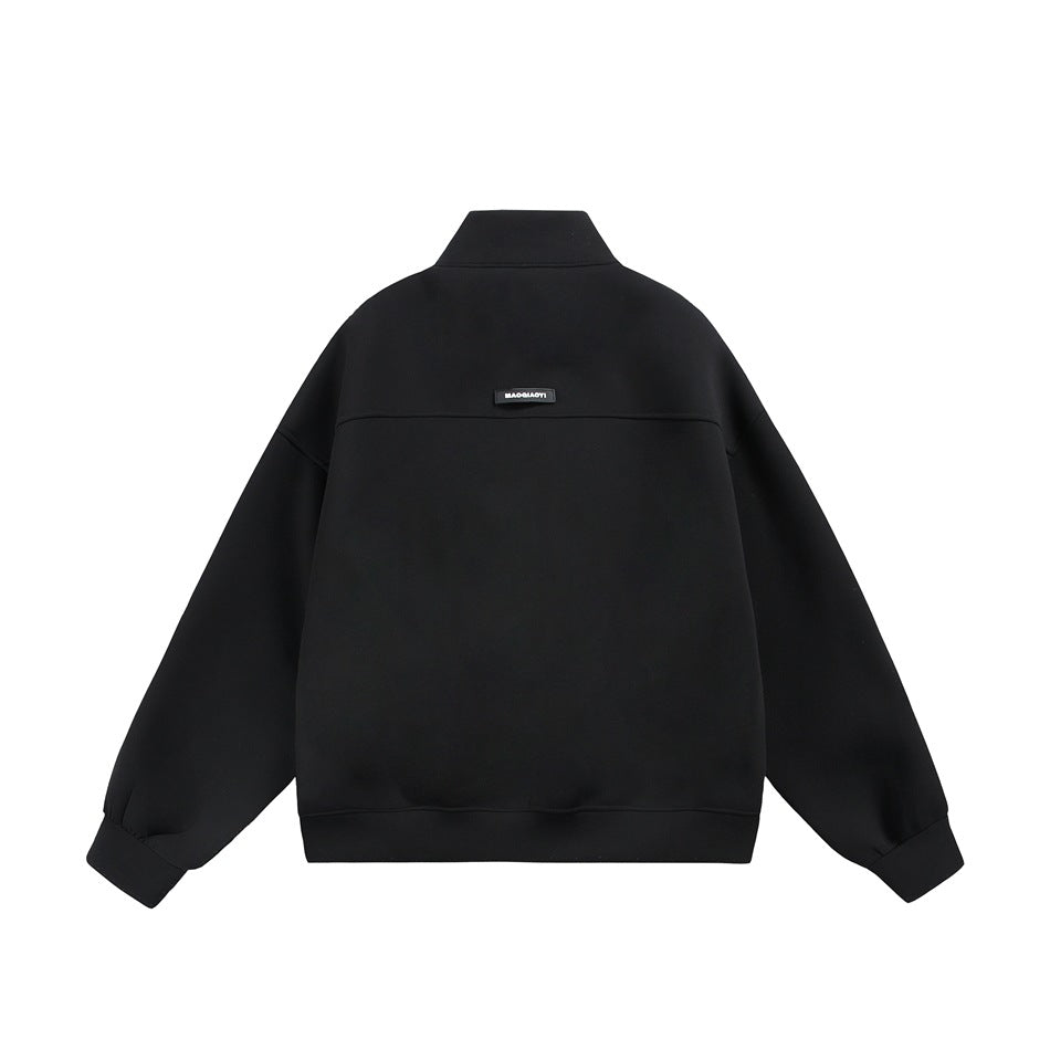 Back view of a black zip-up jacket with a stand collar, dropped shoulders, and a small upper-back label.