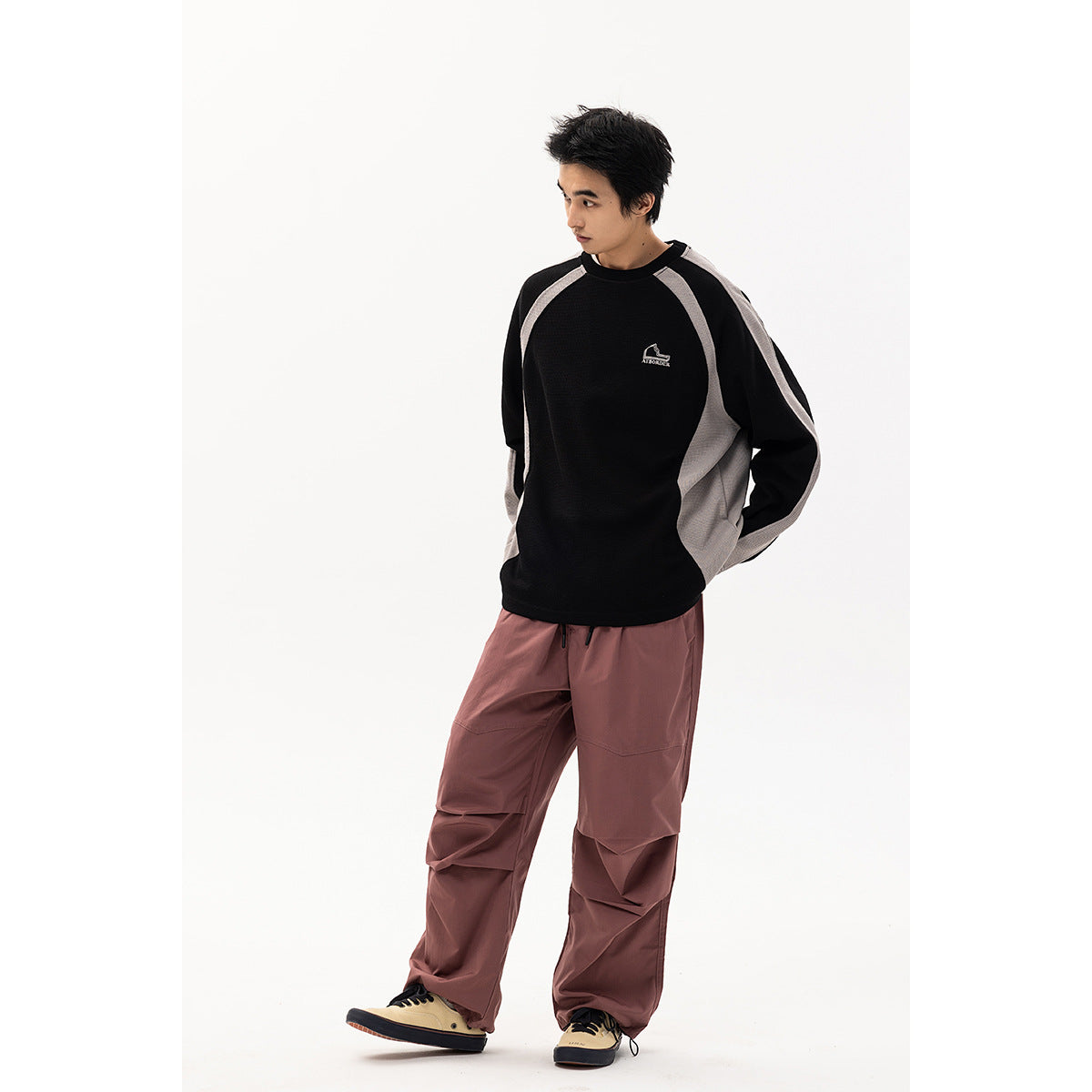Full-length model wearing a black raglan sweatshirt with gray panels and dusty mauve cargo pants.