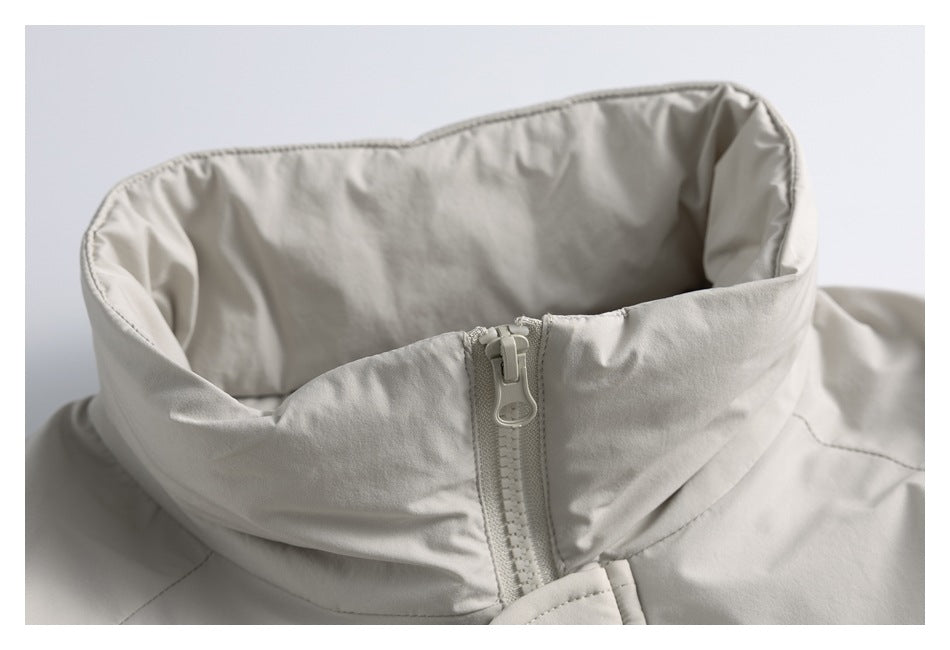 Close-up of a light gray jacket’s tall collar and matching front zipper.