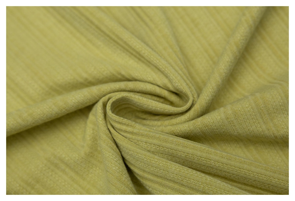 Mustard-yellow textured fabric gathered into a swirl, showing subtle woven stripes and raised details.