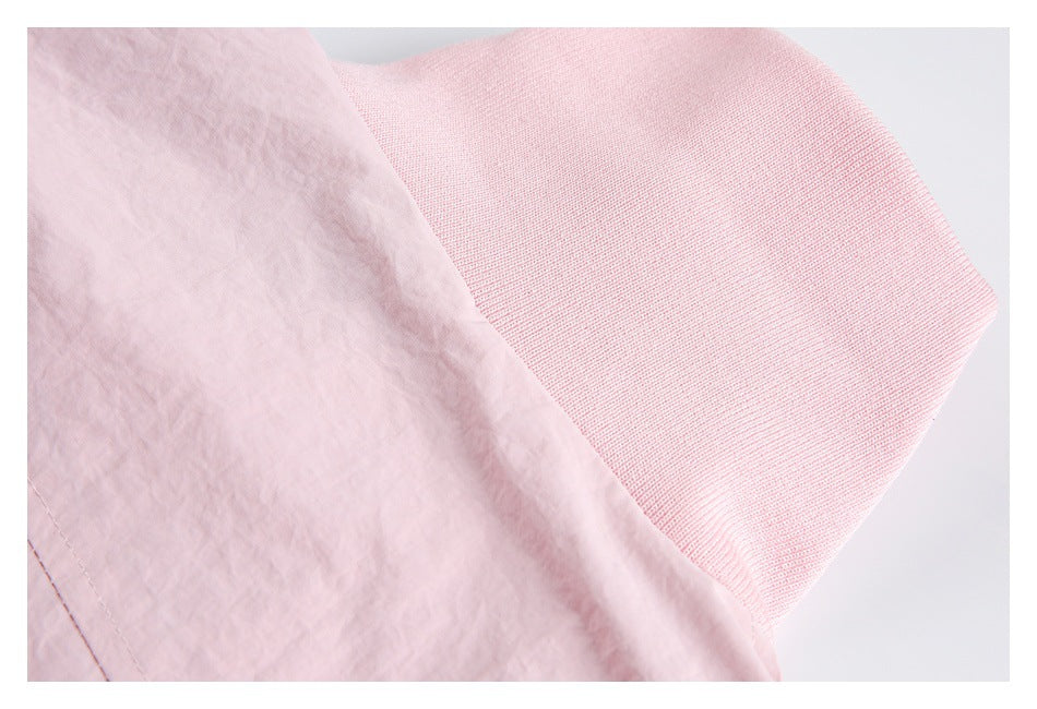 Close-up of a wide pale pink ribbed knit band attached to the jacket fabric.