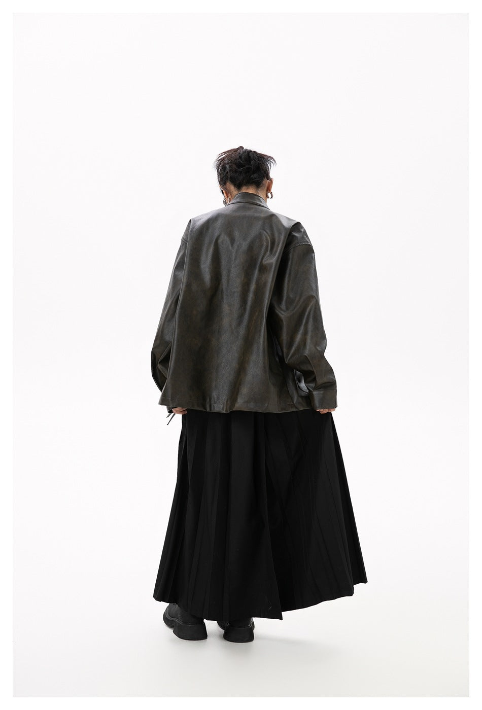 Back view of a model in a dark oversized jacket and long black skirt.