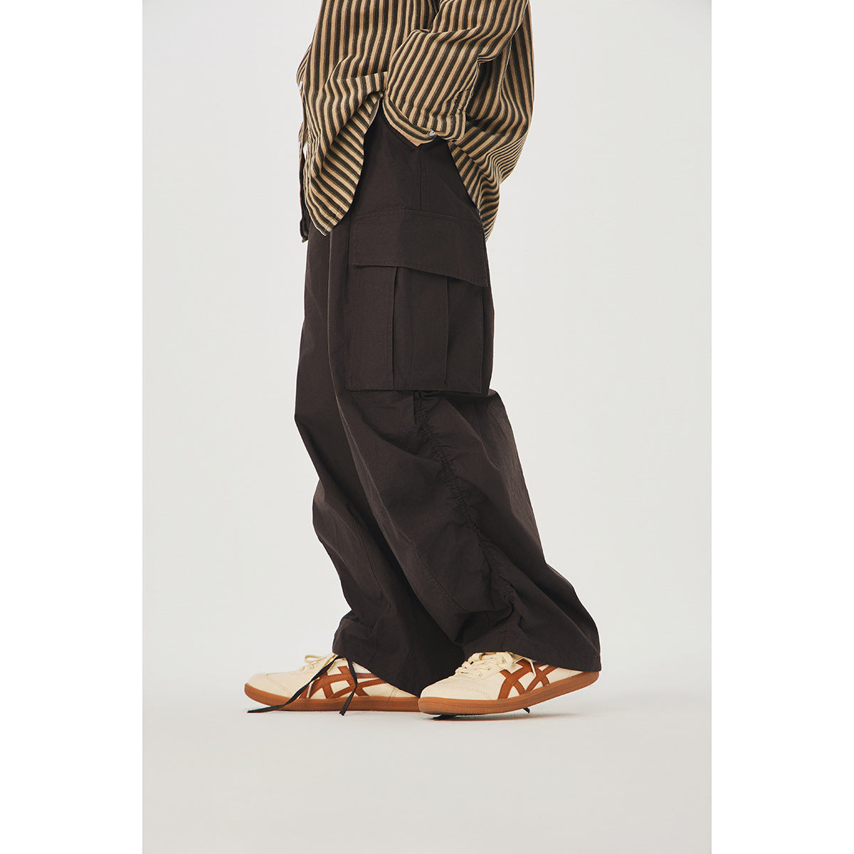 Side view of a model wearing dark brown oversized cargo pants and a striped shirt.
