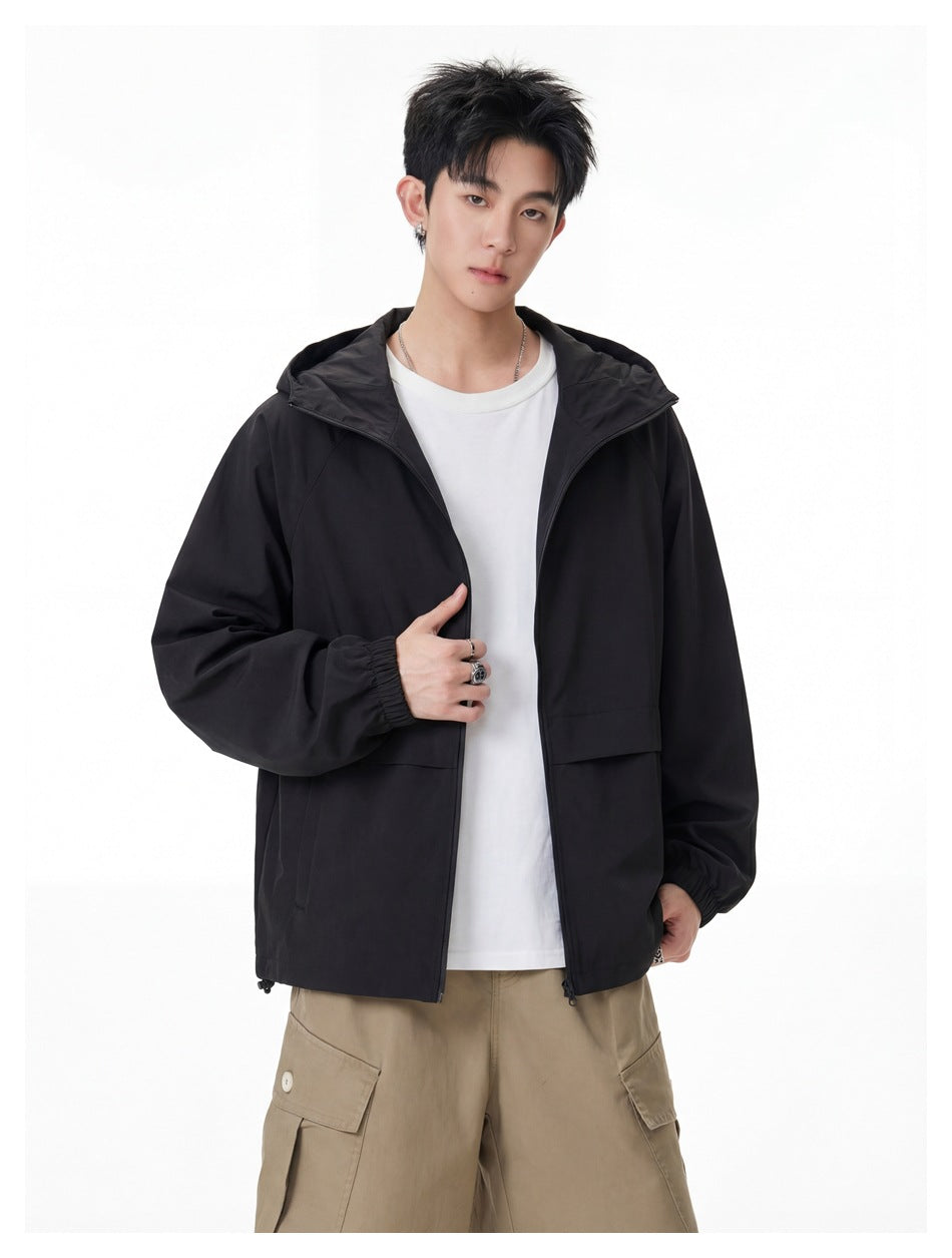 Model wearing an open black hooded jacket over a white T-shirt and beige cargo trousers.