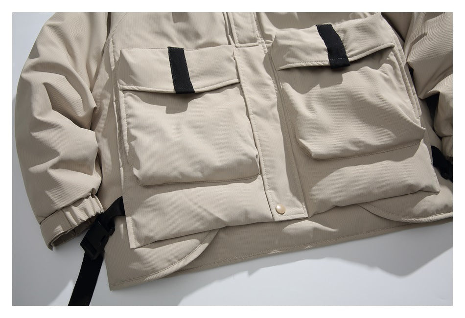 Close view of two large flap pockets with black tabs on the beige jacket front.