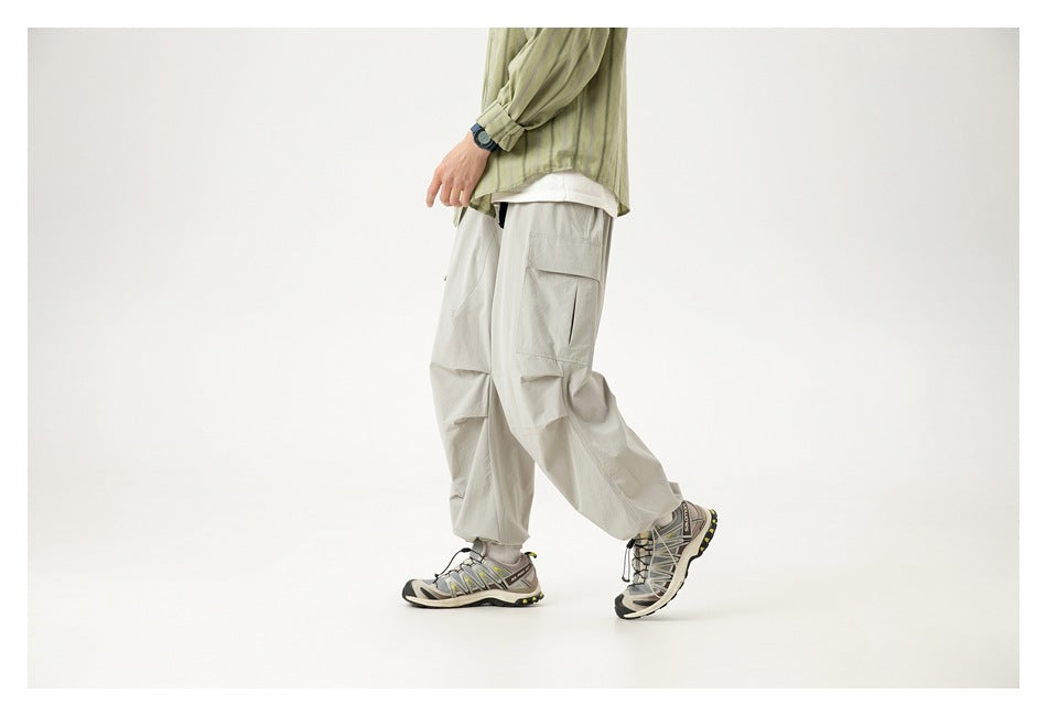 Cropped model walking in loose light gray cargo pants, showing the side pocket and relaxed leg shape.