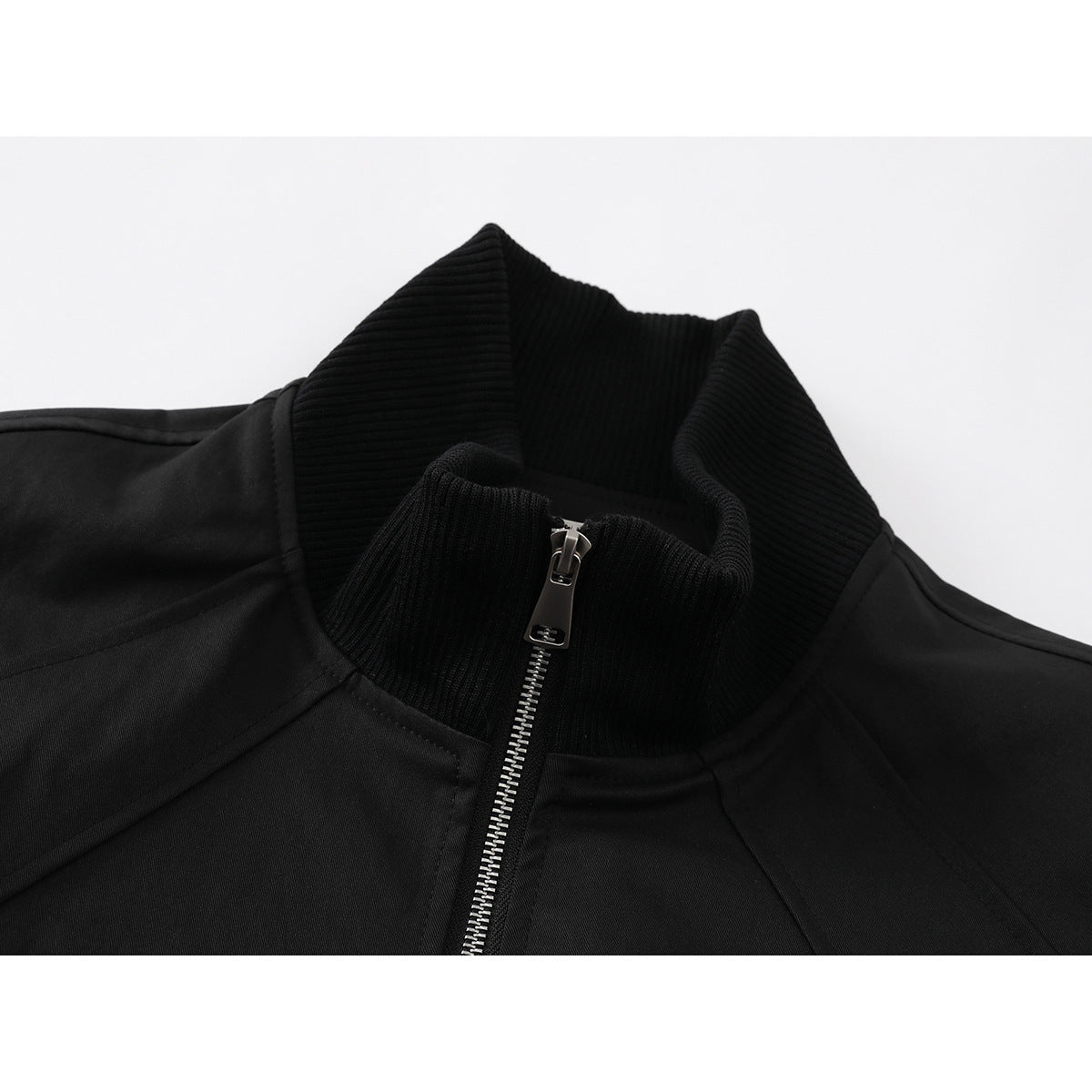 Close-up of a black jacket's ribbed stand collar and silver front zipper.