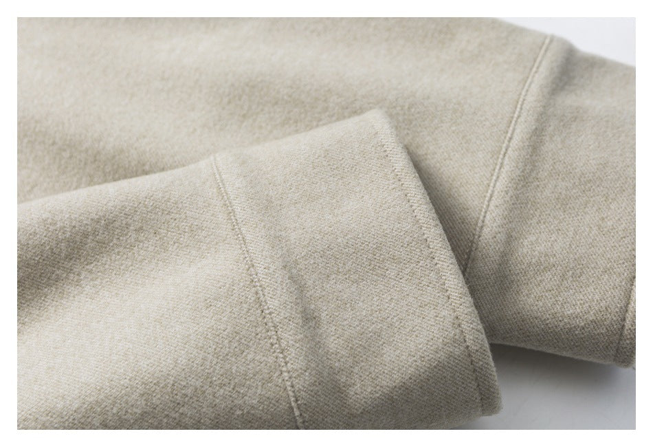 Close-up of a beige woven garment sleeve with a folded cuff and visible stitching.