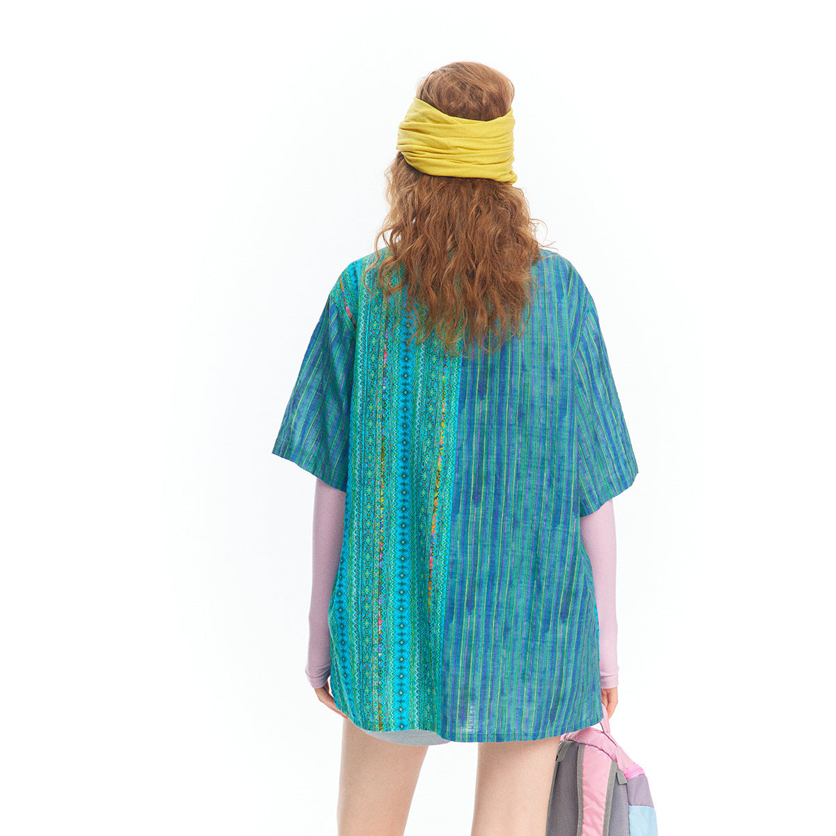 Back view of a model wearing a blue and turquoise striped and geometric-pattern short-sleeve tunic.