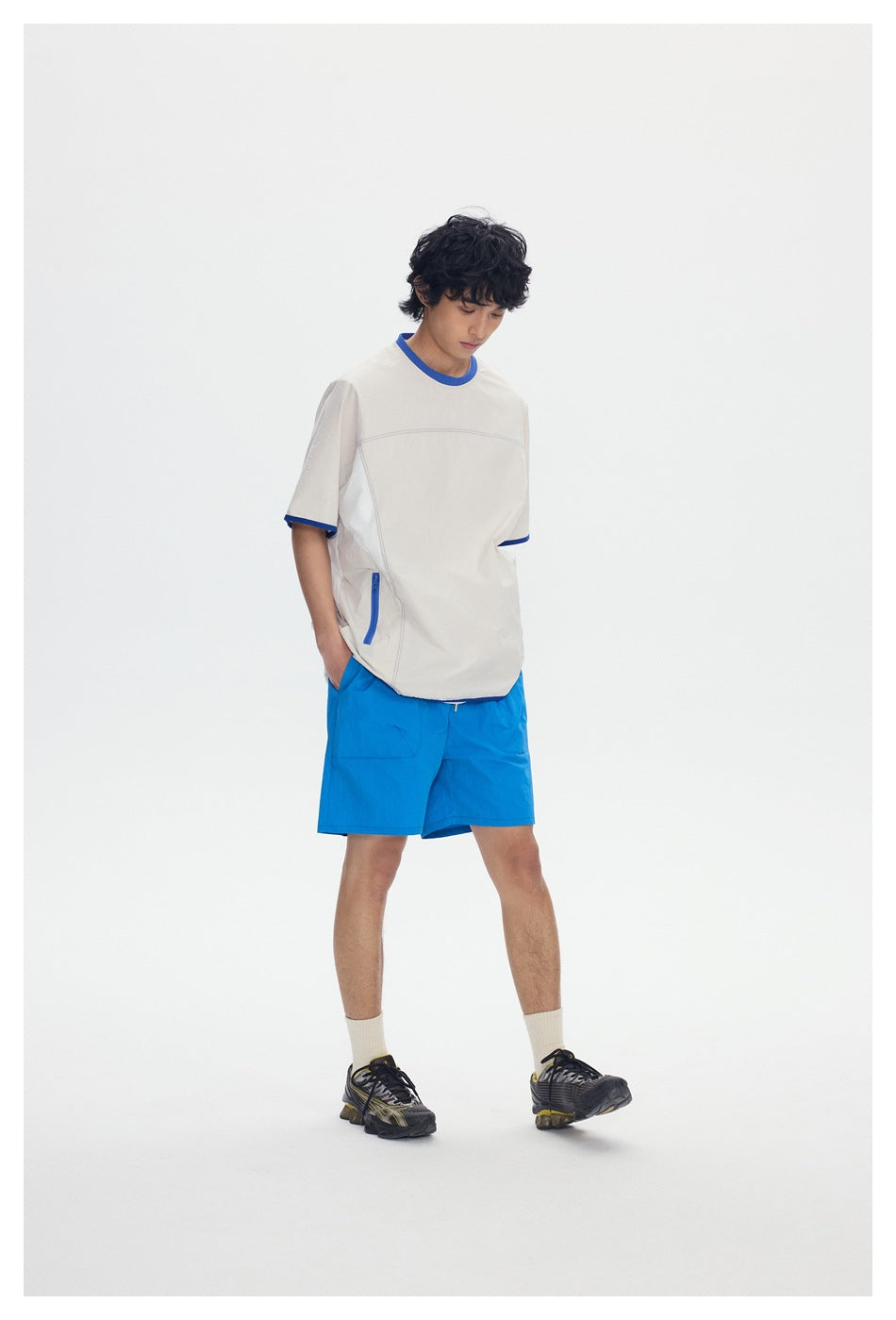Model wearing an ivory short-sleeve shirt with royal blue trim and bright blue shorts.