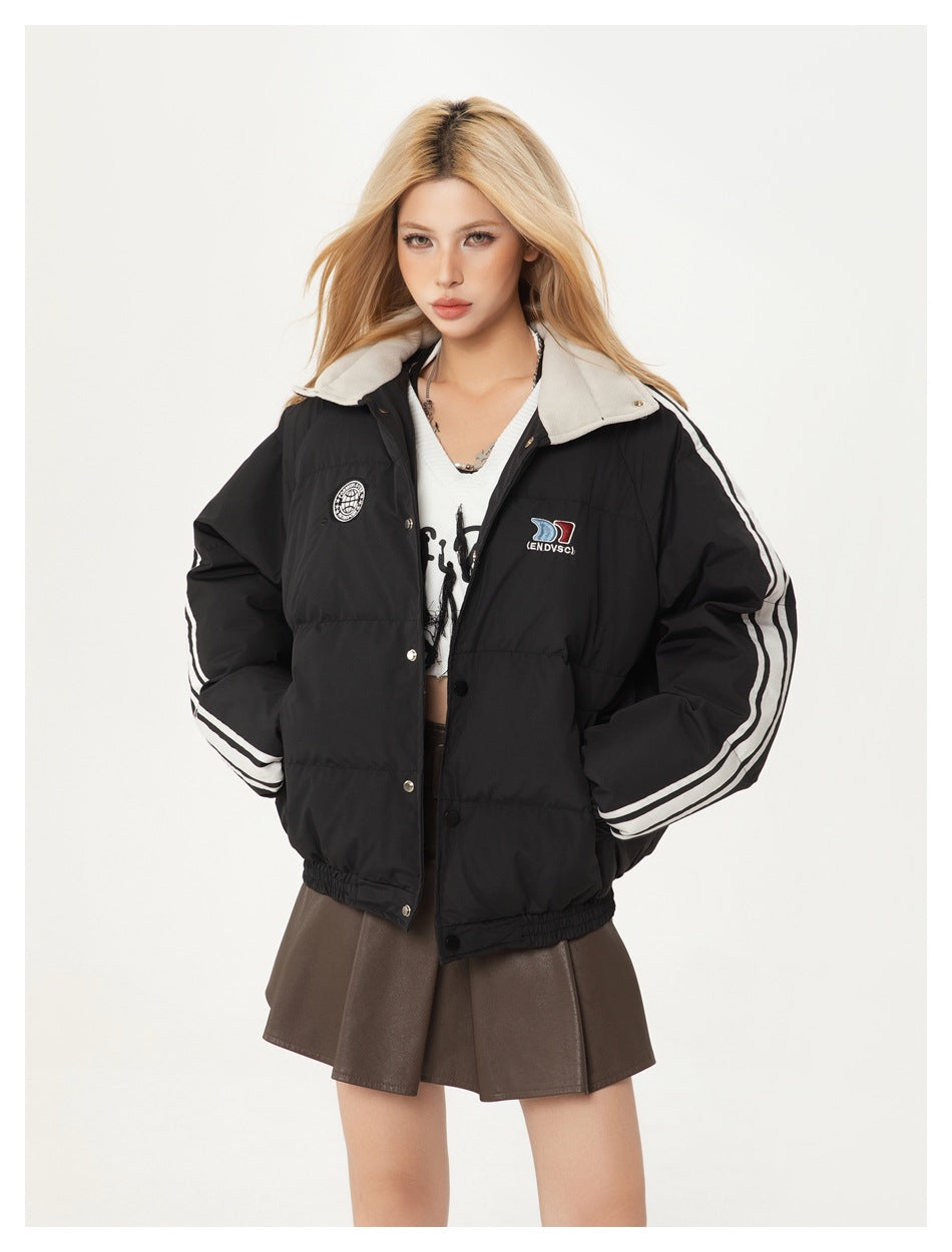 Model wearing a black quilted jacket with a light collar, white sleeve stripes, chest patches and snap buttons.