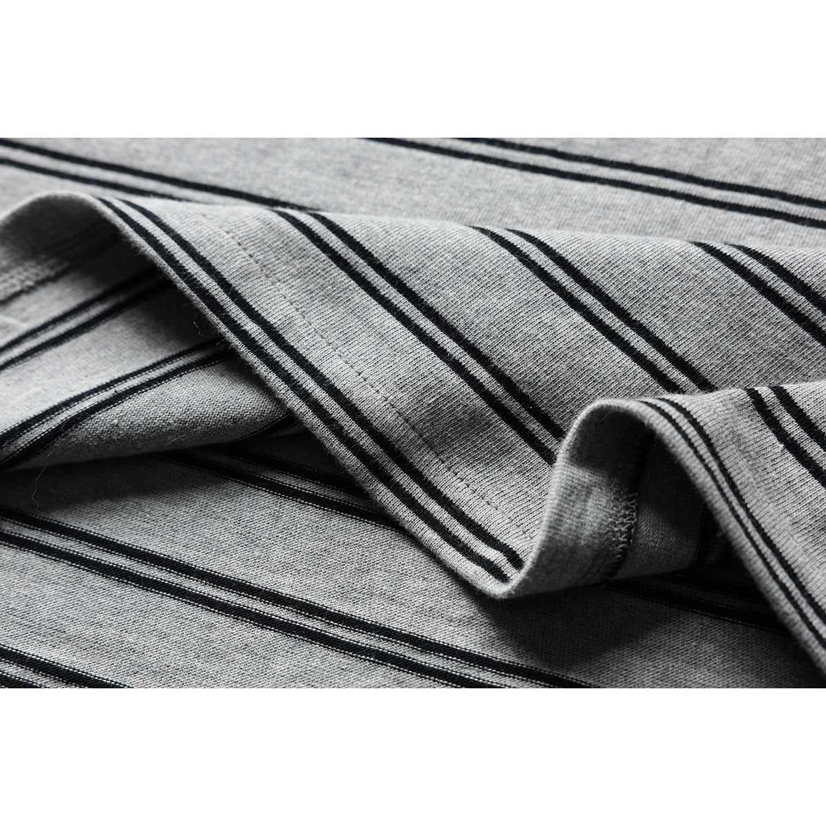 Close-up of gray striped shirt fabric folded to show its knit texture and stitching.