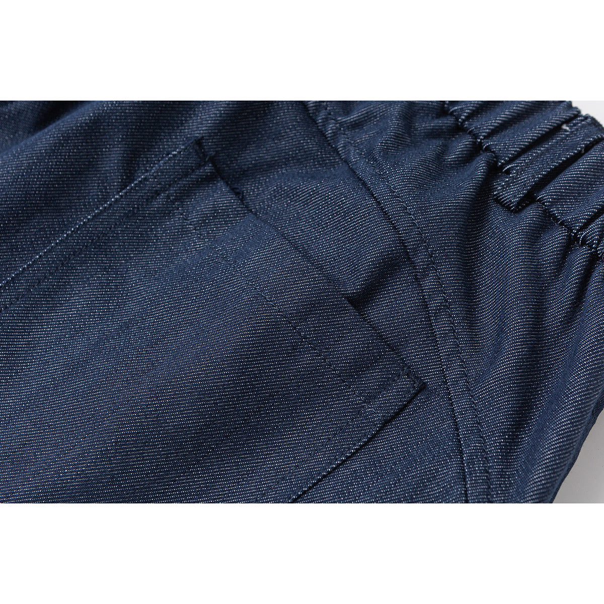 Close-up of navy shorts showing the gathered waistband, seams, and pocket detail.