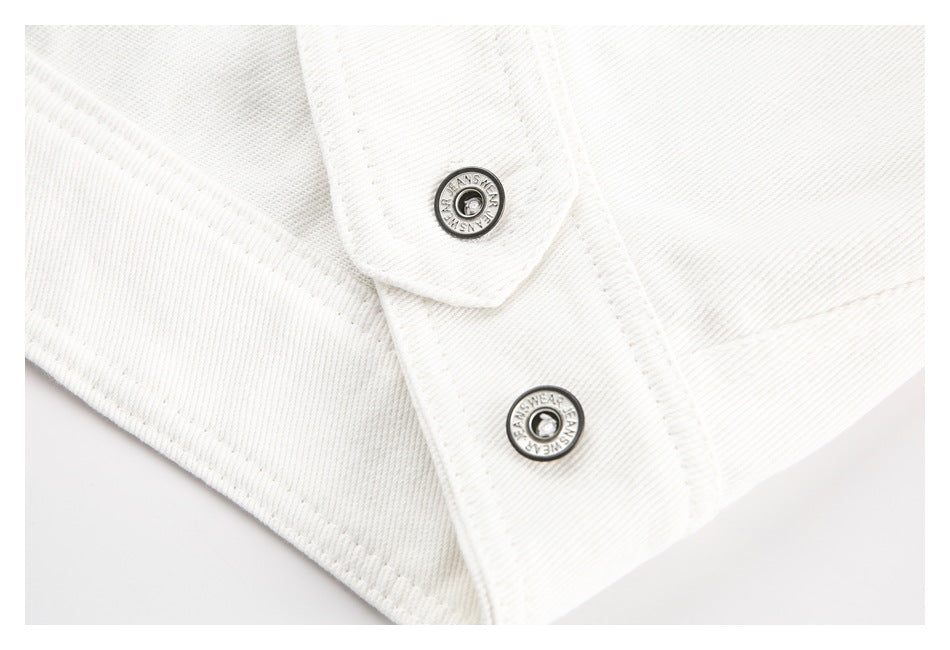 Close-up of two round metal snaps on a white denim placket.
