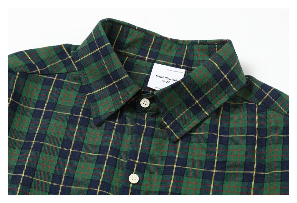 Close-up of a green and navy plaid button-up shirt collar, white buttons, and visible inner label.