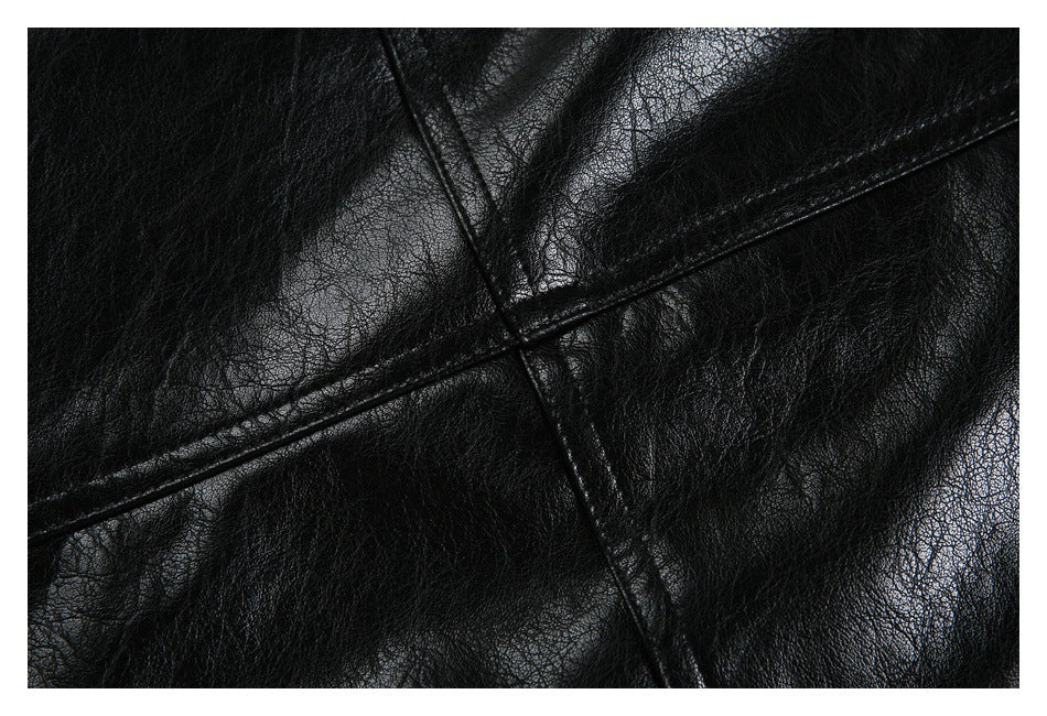 Close-up of black jacket panels with intersecting stitched seams and a textured, glossy surface.