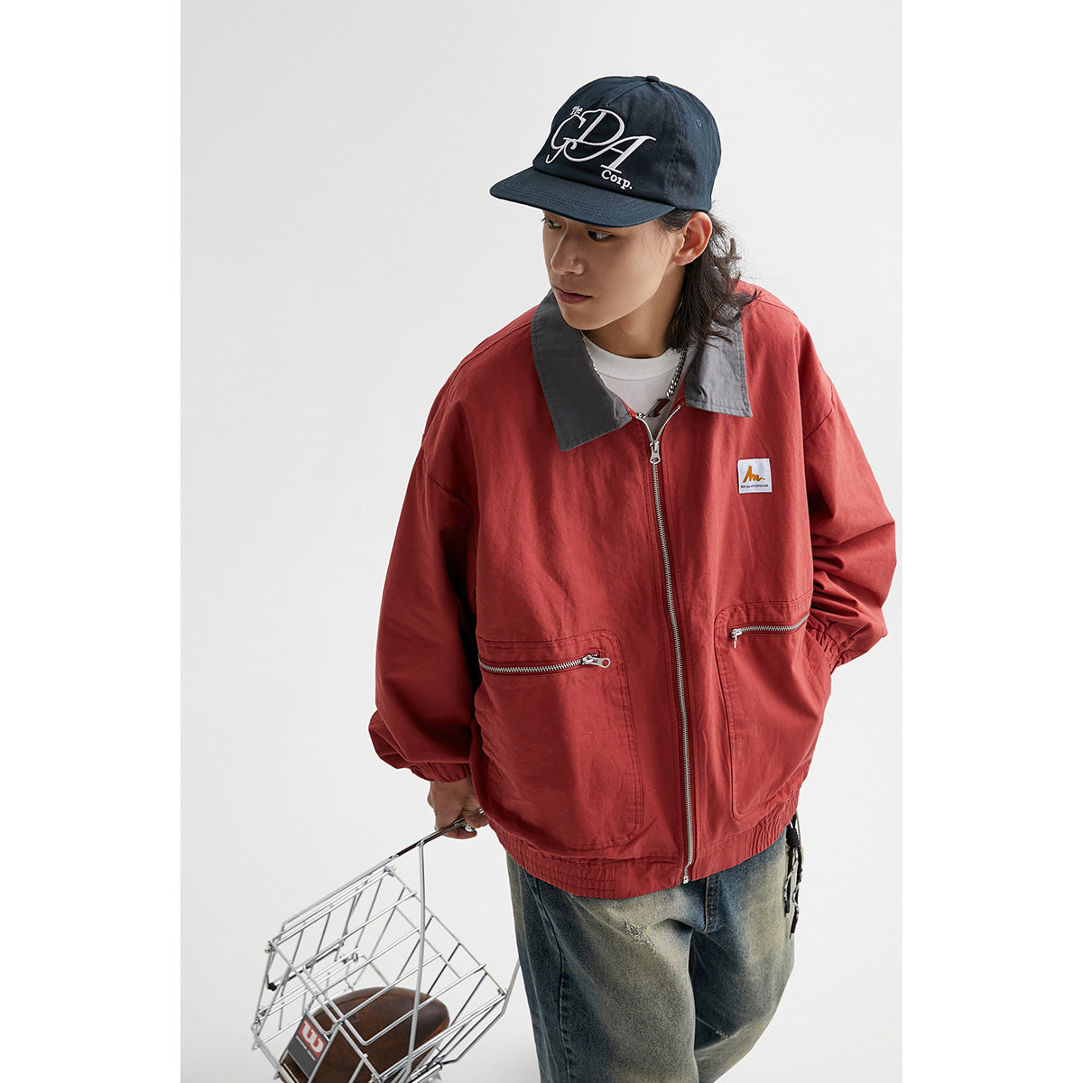 Model wearing a red zip-front jacket with a dark gray collar, elastic cuffs, and two zip pockets.